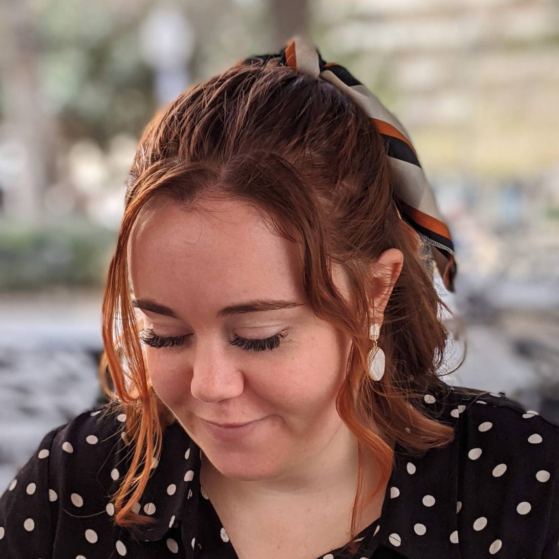Jessica is pictured looking down off camera. She is wearing a black polka-dot dress and has a bow in her hair.